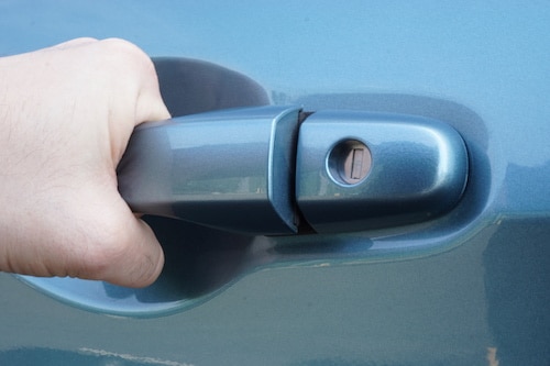 Someone trying to open their car door and it won't open as the keys were locked in the car.